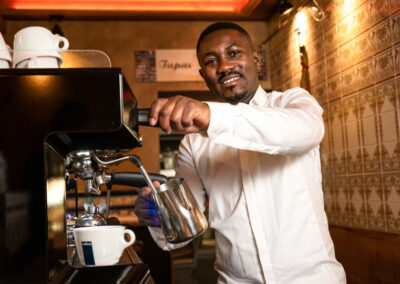 Mitarbeiter an der Bar im Tapas Barcelona, in der Dresdner Alltstadt, bereitet frischen Kaffee zu und schäumt dafür Milch auf